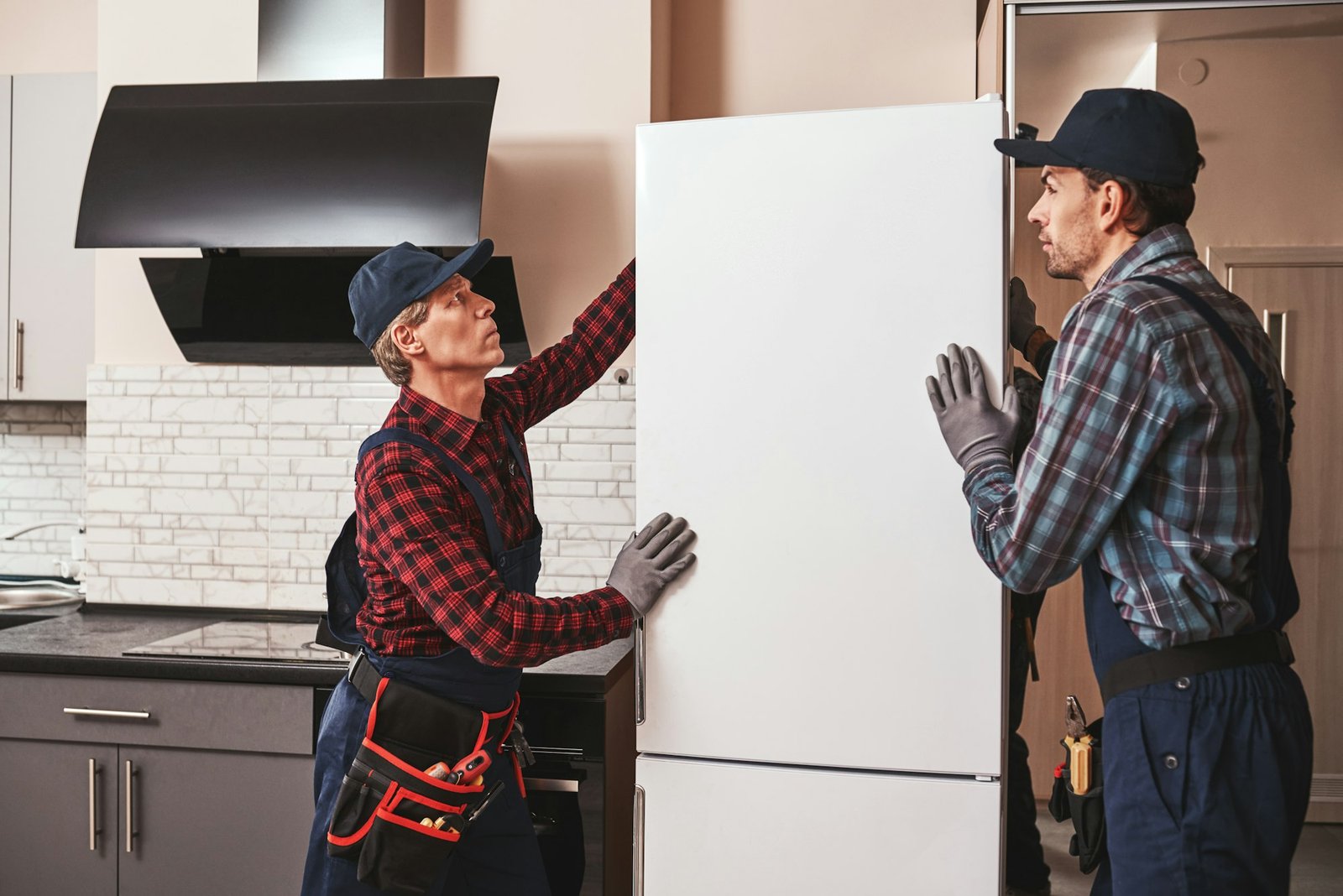 moving again young men mechanics moving refrigerator